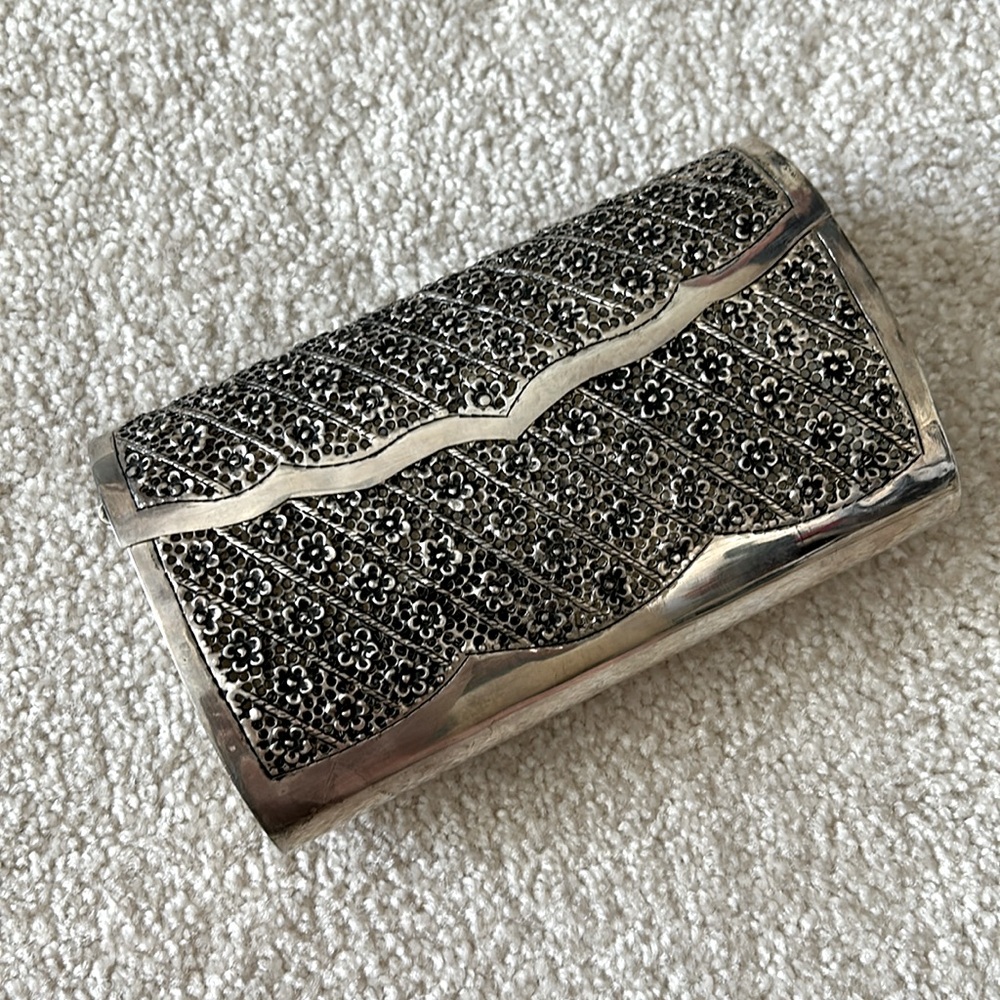 Silver wash covered clutch. Punched metal in a floral pattern.